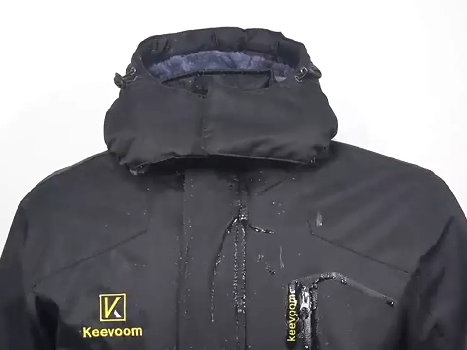 A glass of water poured onto the chest of a black Keevoom winter jacket runs off the shell in streaks